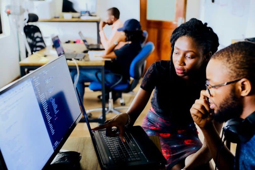 A woman and a man sit side-by-side looking at a computer screen together.
